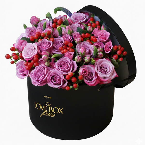 Black 'LOVE BOX' floral arrangement with pink roses and red berries on a white background